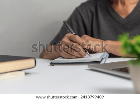 Woman hands with pen writing on notebook in the office.learning, education and work.writes goals, plans, make to do and wish list on desk.	 Royalty-Free Stock Photo #2413799409