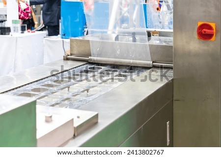 Automatic and continuous plastic box or portion hole tray and stretch film of thermo forming vacuum packing sealing machine in food industrial Royalty-Free Stock Photo #2413802767