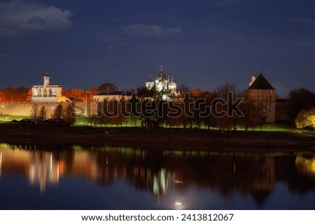 Illuminated Novgorod Kremlin in the evening twilight is reflected in the water of the Volkhov River. Veliky Novgorod, Russia. Royalty-Free Stock Photo #2413812067