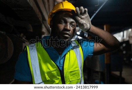 African-American engineers or workers in work clothes wearing safety helmets with dirty bodies. Wipe sweat from his face. While repairing machinery in industrial factories in industrial concept