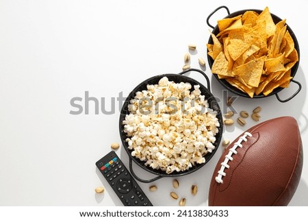 Popcorn and chips with a rugby ball on a light background Royalty-Free Stock Photo #2413830433
