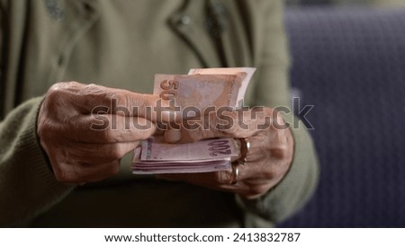 old woman holding paper currency Royalty-Free Stock Photo #2413832787