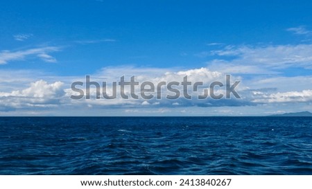 Panorama of the open sea on a cloudy day. View of the sea surface, small waves and white cumulus clouds above the horizon. Sea background.                                Royalty-Free Stock Photo #2413840267