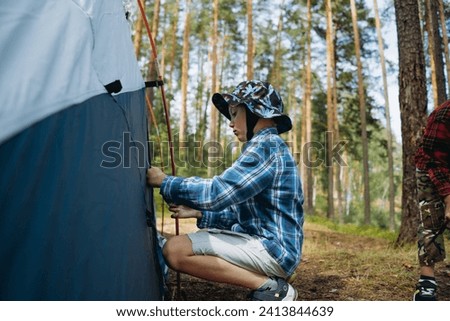 cute little caucasian boy putting up a tent. Family camping conceptsunset shadows from trees. Family camping concept. High quality photo