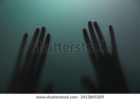 Silhouette of creepy ghost behind glass against color background, closeup
