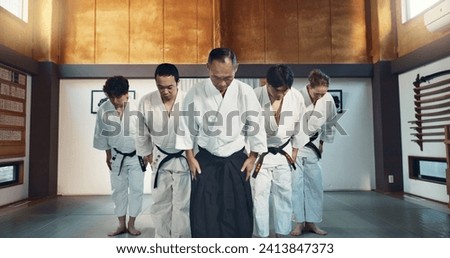 Martial arts group, men and bow for exercise, respect or honor for fight, conflict or competition in dojo. Senior Japanese sensei, black belt students and aikido with training, workout or discipline Royalty-Free Stock Photo #2413847373