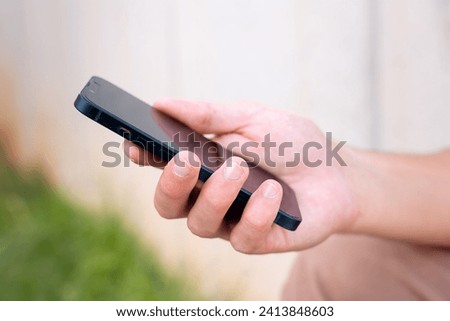  close up of young boy using smartphone app outdoors.