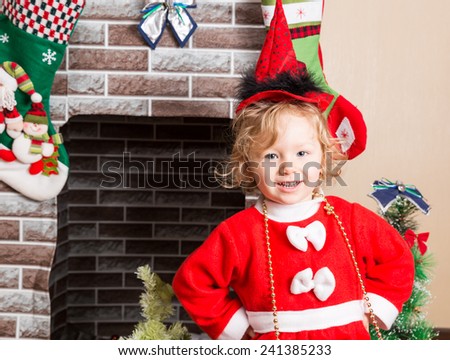 Little girl dressed costume Santa Claus by fireplace. Christmas and New Year