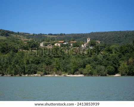 Panoramic view of the natural area of the Maroño reservoir in Álava on a sunny day with a high water level surrounded by trees, vegetation and small houses in the middle of the forest.