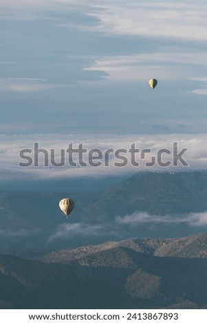 La Garrotxa Landscape from above with two hot air balloons flying flying over the clouds and the volcanic zone. Vertical picture.