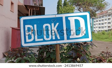 The house address sign is written on a blue and white board made of zinc plate