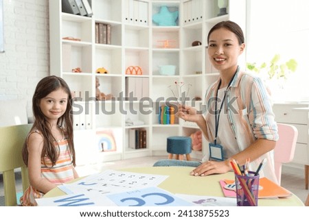Female Asian speech therapist with logopedic probes and little girl in office Royalty-Free Stock Photo #2413875523