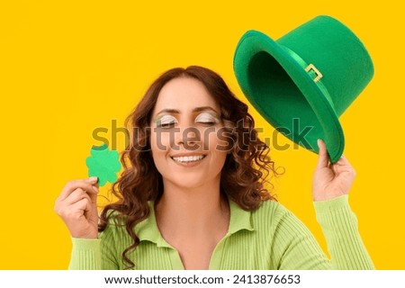 Woman with green paper clover and hat on yellow background. St. Patrick's Day celebration