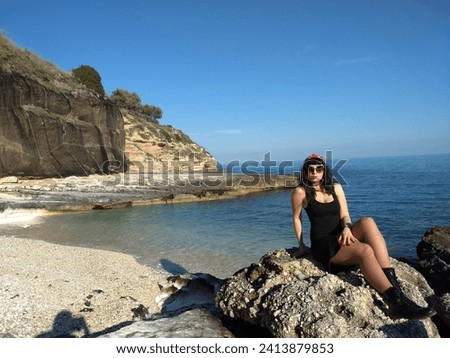 Mediterranean pin-up strikes a pose on a seaside cliff. Vintage allure meets coastal charm in this stock photo. Perfect for fashion, lifestyle, and travel projects.