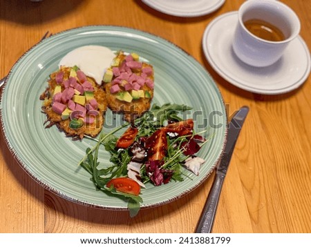 Gourmet potato pancakes topped with ham and avocado, served with salad and espresso coffee.