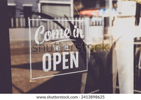 Text on vintage black sign "Come in we're open" in cafe.