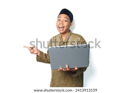 surprised asian muslim man pointing to beside with holding laptop isolated on white background
