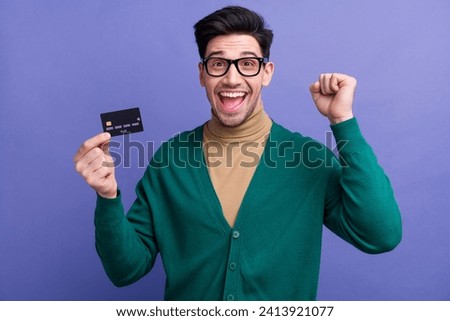 Photo of overjoyed cheerful man wear trendy clothes hold plastic card rejoice wealth transaction money isolated on purple color background