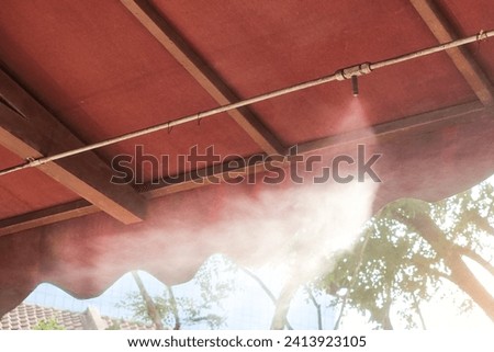 Closeup eco system with nozzle spraying water mist to cool down the very warm ambient temperature at corridor Royalty-Free Stock Photo #2413923105