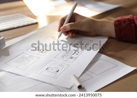 Woman drawing cartoon sketches at workplace, closeup. Pre-production process