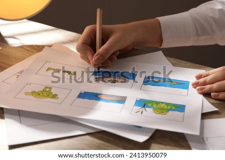 Woman drawing cartoon sketch in storyboard at workplace, closeup. Pre-production process