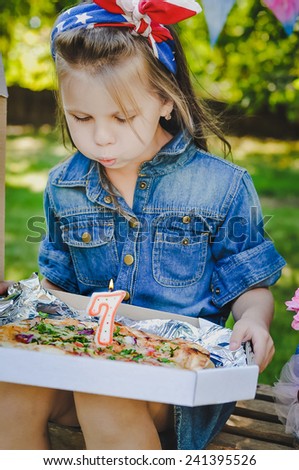 Beautiful birthday 7 years old girl outdoors with pizza instead of birthday cake