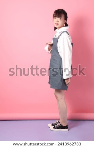 Cheerful lovely young asian woman in overalls casual clothes with gesture of hands pointing isolated on pink background. St Valentine's Day, Women's Day, Birthday