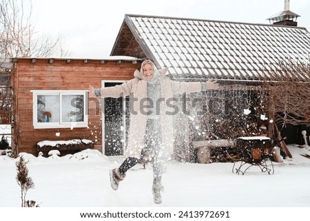 Woman gardener in a landscape with snow, coastal snow, winter, coastal. Jump and snow game. Cottage in the snow.