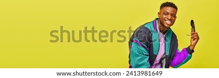 cheerful african american man in bright jacket with sunglasses looking at camera on yellow, banner
