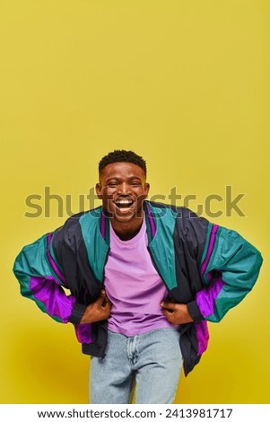excited african american man in fashionable casual attire laughing at camera on yellow backdrop