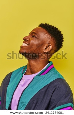 portrait of laughing african american man in trendy casual attire looking away on yellow backdrop