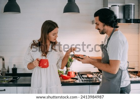 International Women's Day. Young couple in the morning in the kitchen at home. A man cooks a woman a festive breakfast on March 8 in a beautiful stylish kitchen.