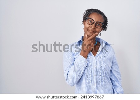 African woman with dreadlocks standing over white background wearing glasses looking confident at the camera smiling with crossed arms and hand raised on chin. thinking positive. 