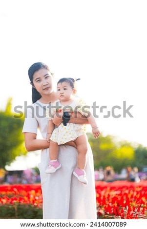 Mother and child in the flower field,Beautiful mother and daughter in spring poppy flower field. Mom holds her child daughter in the flowering meadow piggyback ride. Happy motherhood.