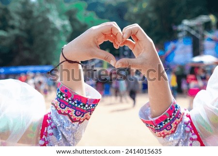 woman raised her hands and made heart symbol to express meaning of love friendship and kindness to her friends and lovers. woman uses her hands to make a heart symbol that means love and friendship. Royalty-Free Stock Photo #2414015635
