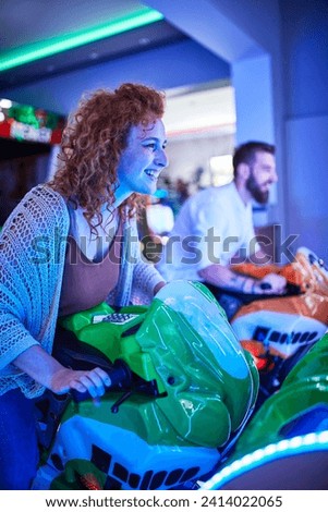 Woman playing and having fun with a driving simulator in an amusement arcade Royalty-Free Stock Photo #2414022065