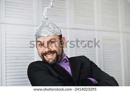 Bearded funny man in cap of aluminum foil. Concept art phobias. Conspiracy theory. Conspiracy. Insanity. Royalty-Free Stock Photo #2414023295