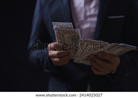 Man offers set of bills worth hundred dollars. Hands close up. Venality, bribe, corruption concept. Hand giving money. Hand receives money from businessman. Royalty-Free Stock Photo #2414025027