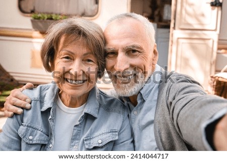 Old senior elderly couple vlogging blogging taking selfie photo in camper van trailer motor home caravanning together on holidays in a trip voyage