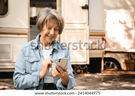 Cheerful caucasian senior old elderly grandmother businesswoman freelancer using cellphone smart phone for social media, travel blog vlog online while driving motor home trailer