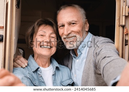 Happy active old senior elderly travel bloggers vlogging grandparents on videocall on social media while driving camper van caravanning in trailer motor home