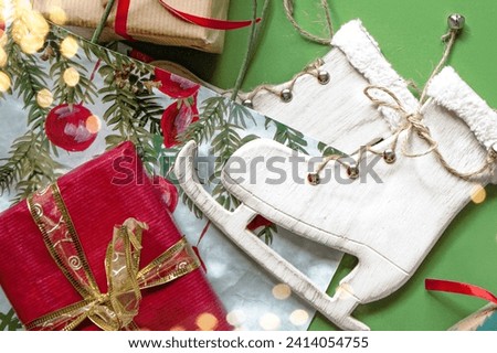 Wooden decorative skates and Christmas gifts are on a green background. A bright background with garlands for the celebration of the New Year.