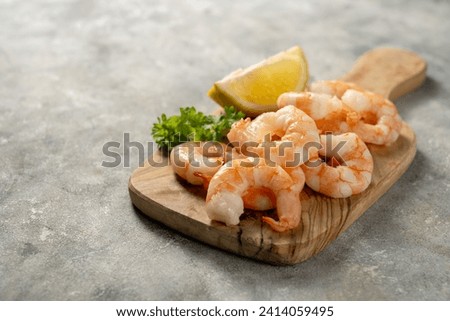 Cooked shrimps over wooden cutting board. Seafood, bright background. 