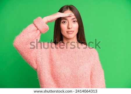 hispanic pretty woman greeting the camera with a military salute in an act of honor and patriotism, showing respect
