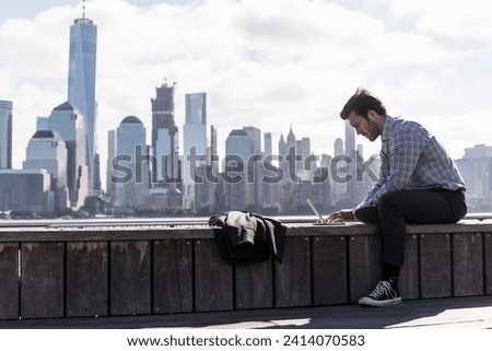 Usa- man using tablet at new jersey waterfront with view to manhattan