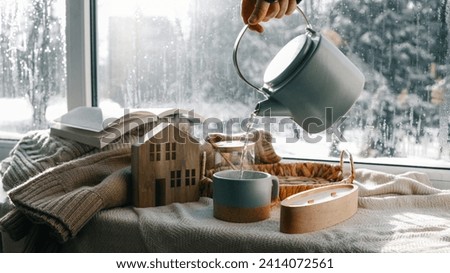 Pouring a cup of tea, cozy home photo.
