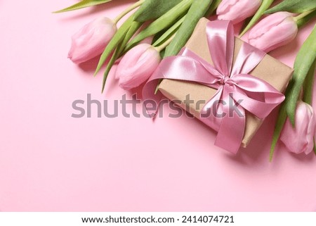 Beautiful pink tulips and craft gift on colored background 