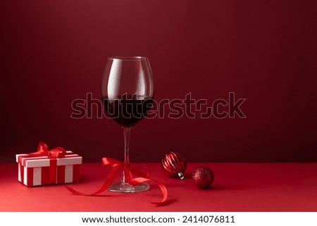 Glass of red wine with a bow on a red background art photography