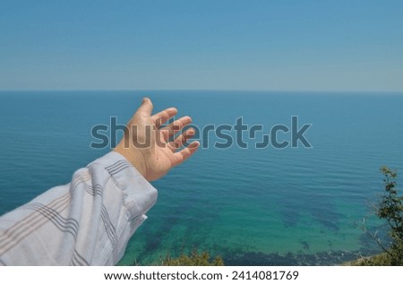 Hand pointing direction to clear horizon overlooking sea and blue sky Royalty-Free Stock Photo #2414081769