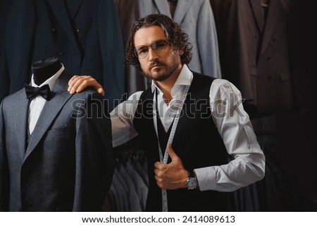 Concept dressmaker handmade couturier. Handsome man tailor in glasses fitting bespoke suit to men in atelier or tailoring studio.